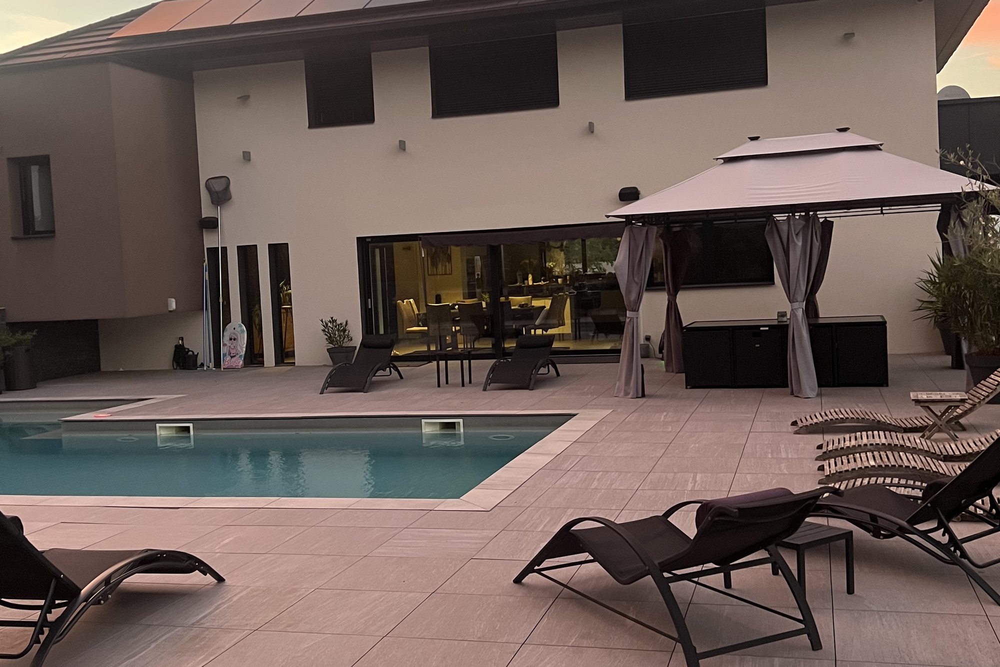 Piscine chauffée, transats et gazebo dans la lumière dorée du soir