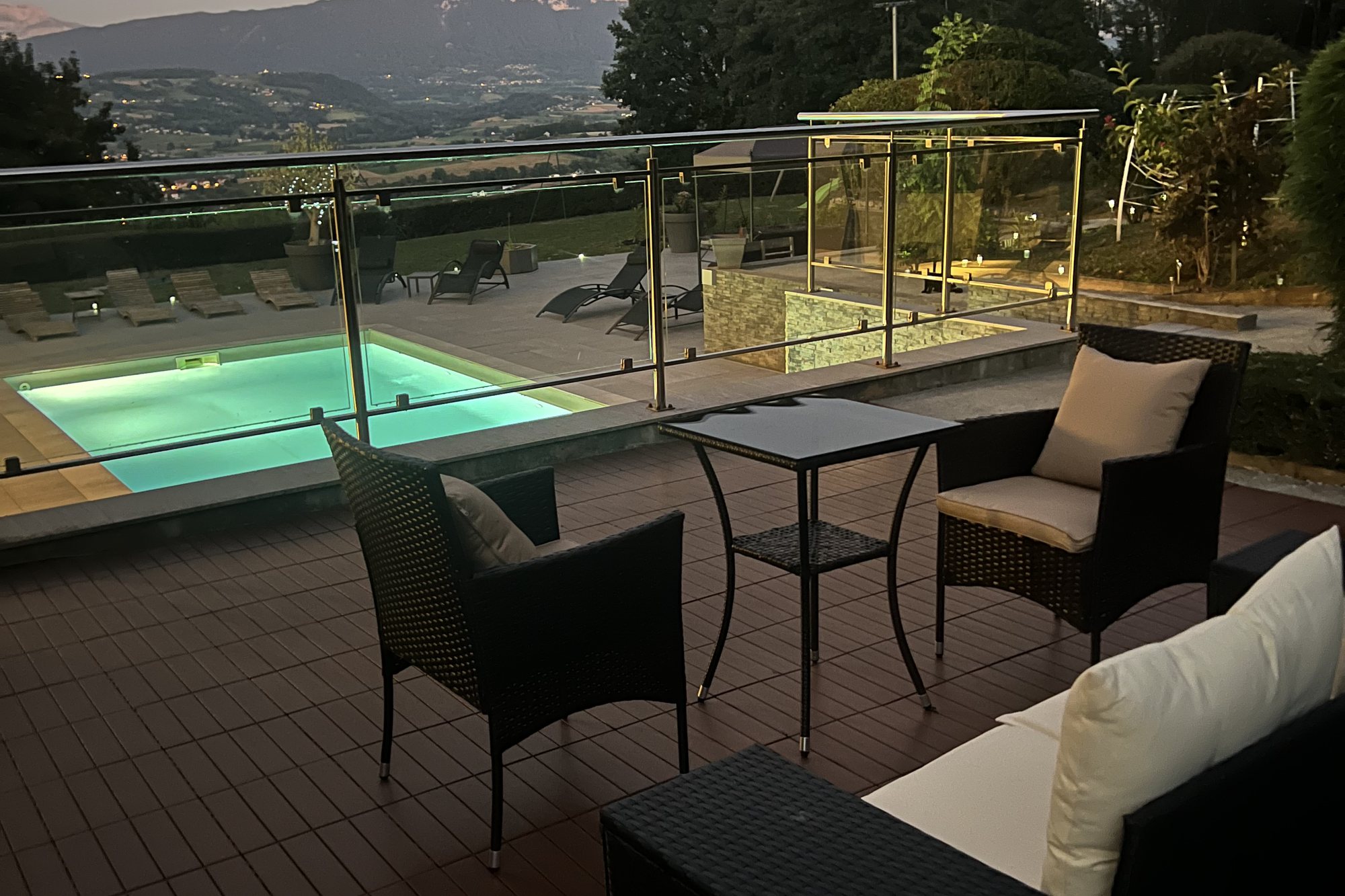 Salon extérieur sur la terrasse en bois, face à la vallée au crépuscule