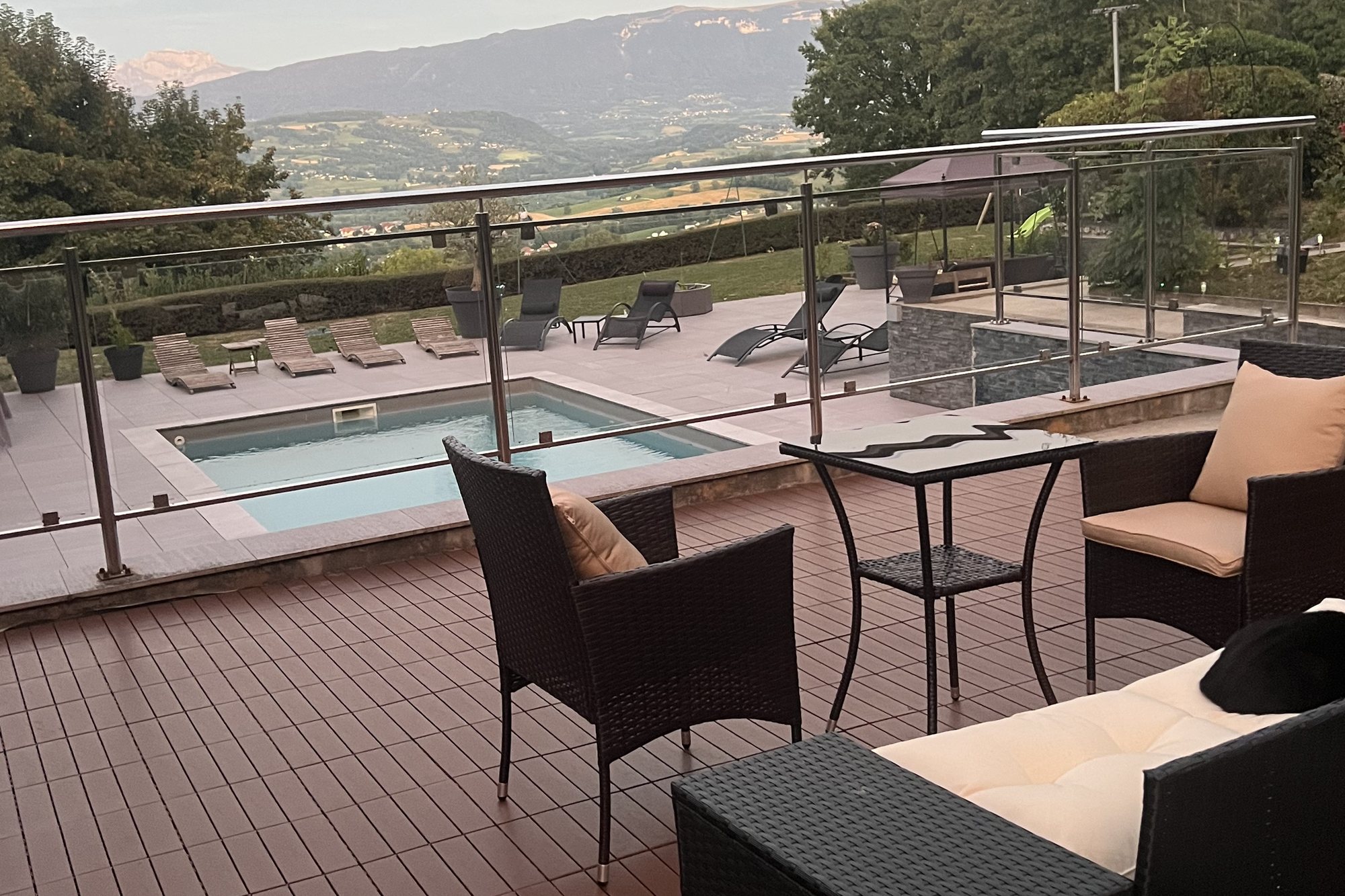 Salon extérieur sur la terrasse en bois, face à la piscine et à la vallée