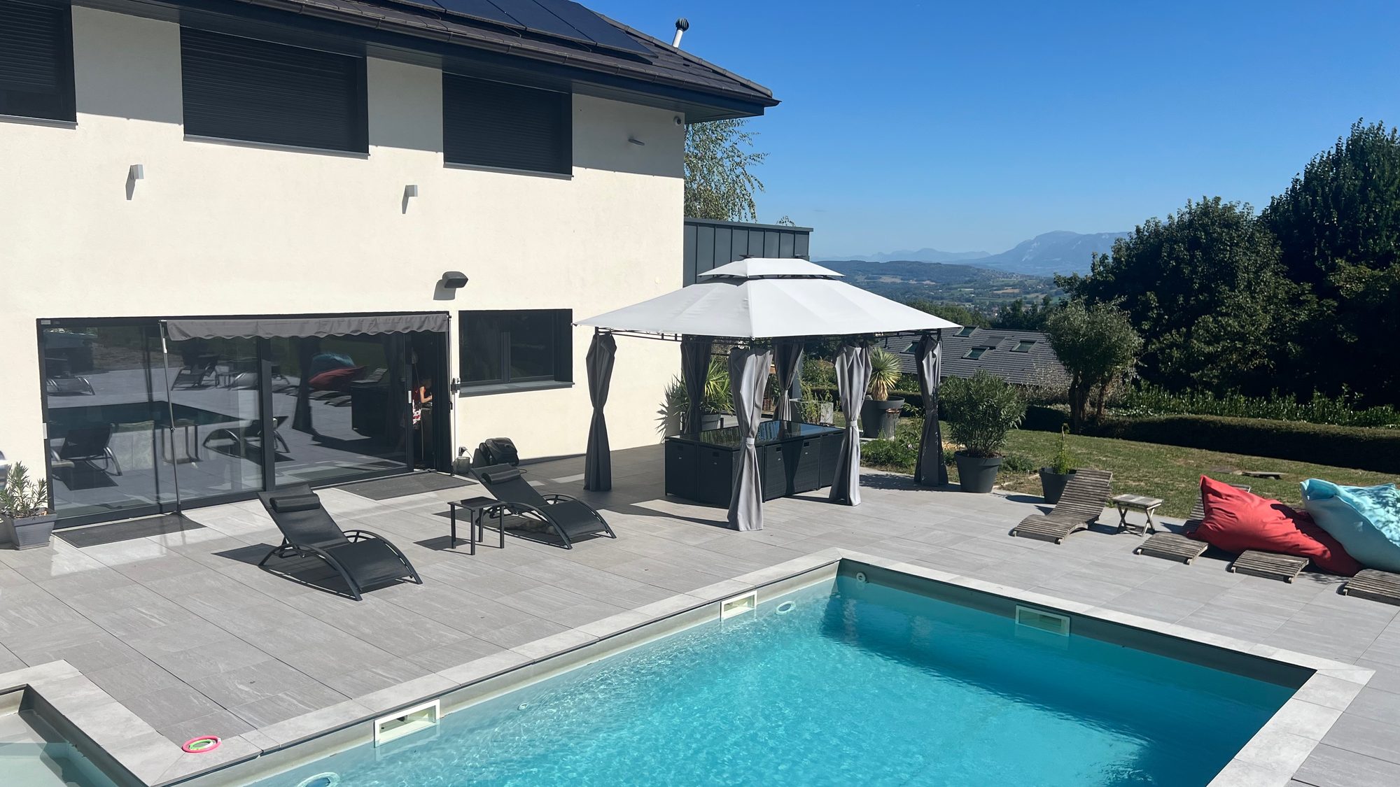 Terras met ligstoelen bij het zwembad van Villa Gai Moulin